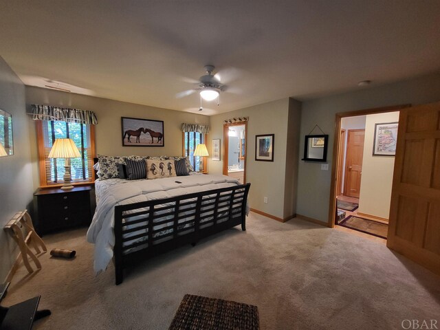 bedroom featuring a ceiling fan, light colored carpet, baseboards, and ensuite bathroom