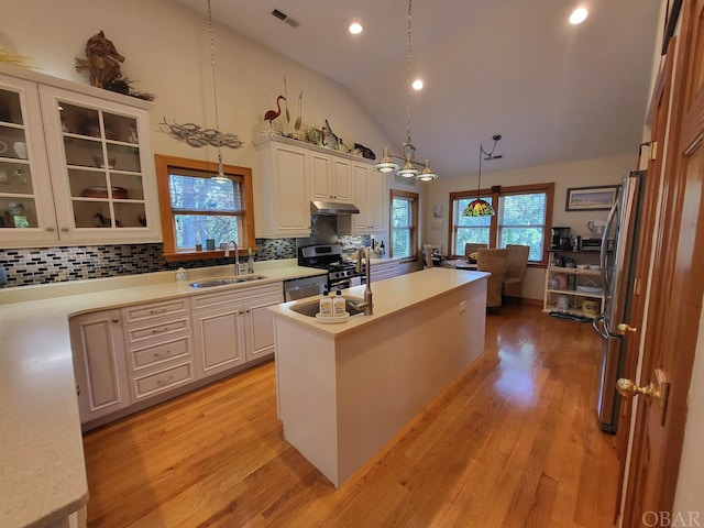 kitchen with light countertops, a sink, decorative light fixtures, and a center island