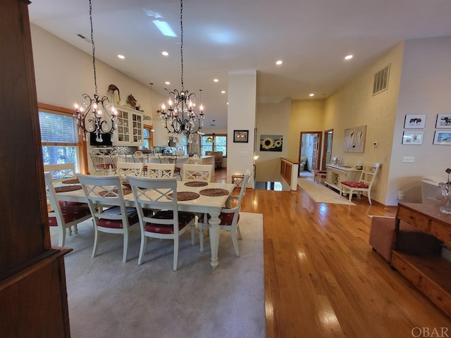 dining room with a towering ceiling, visible vents, wood finished floors, and recessed lighting