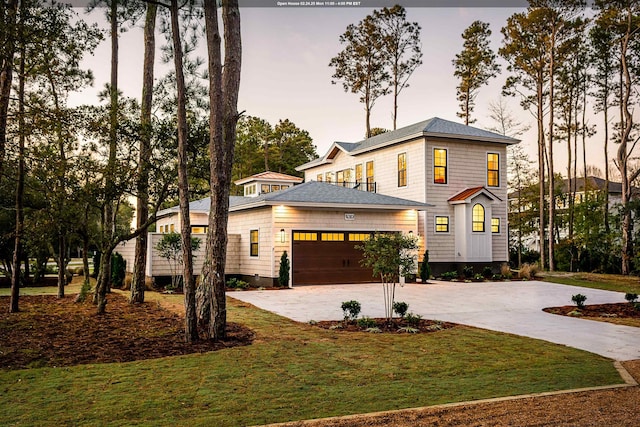 view of front facade with an attached garage, a lawn, and concrete driveway