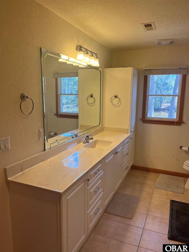 bathroom with a textured ceiling, tile patterned floors, visible vents, and a healthy amount of sunlight