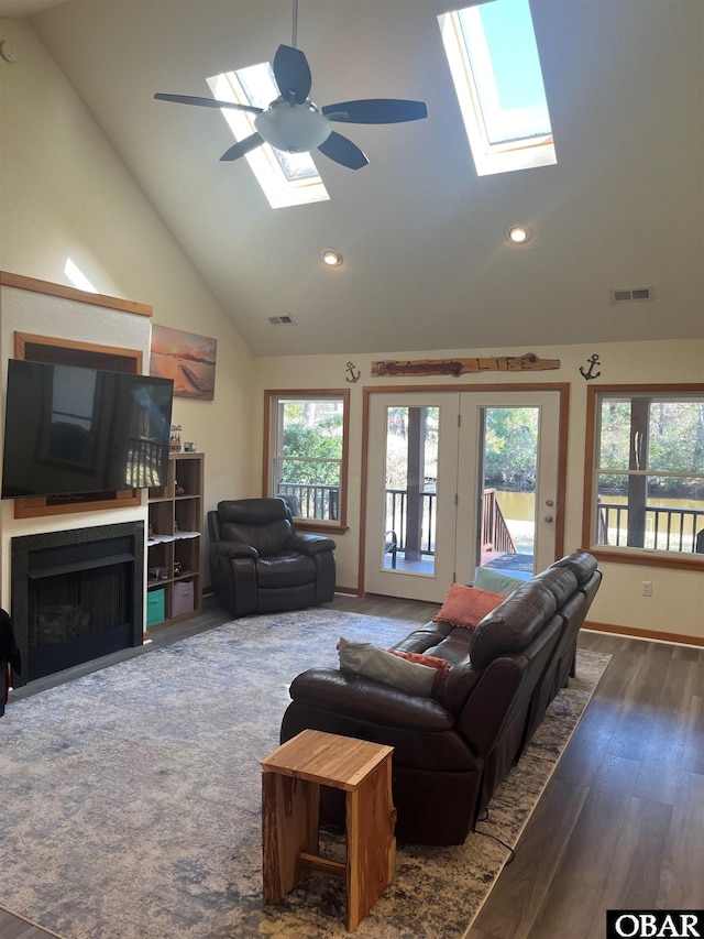 living room with a skylight, a fireplace with flush hearth, visible vents, and dark wood-type flooring