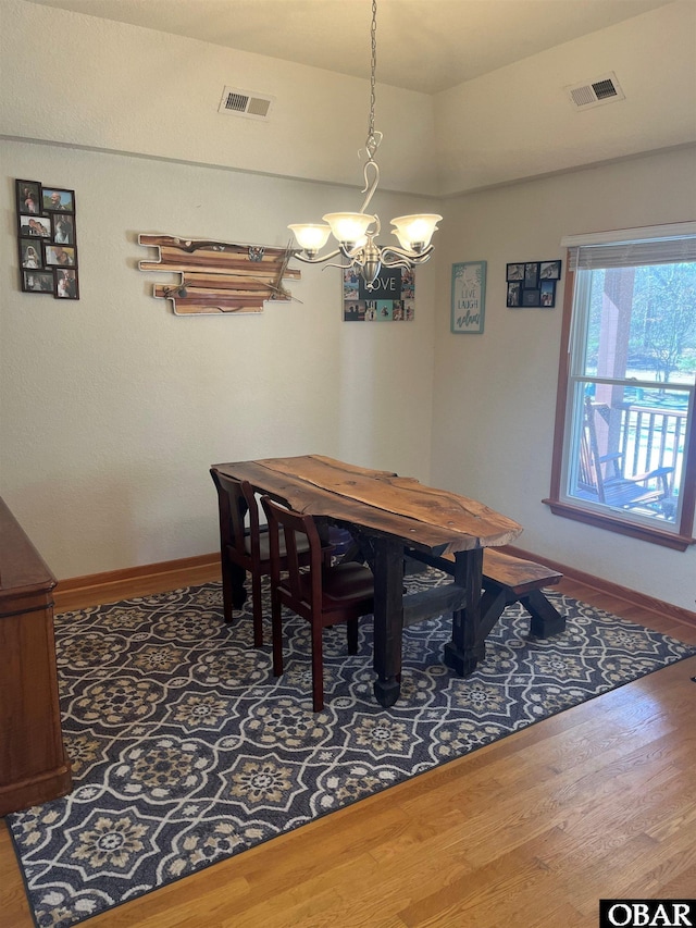 dining room with a notable chandelier, wood finished floors, visible vents, and baseboards