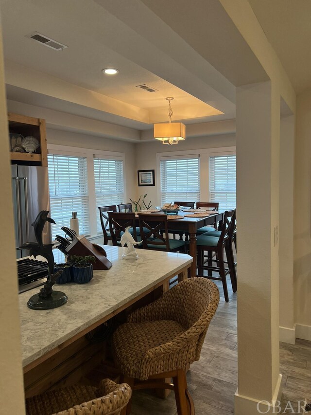 dining area featuring recessed lighting, visible vents, baseboards, light wood-style floors, and a tray ceiling