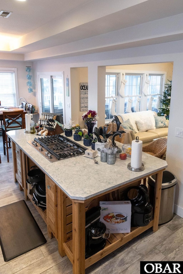 kitchen featuring light wood-style flooring, stainless steel gas stovetop, visible vents, and open floor plan