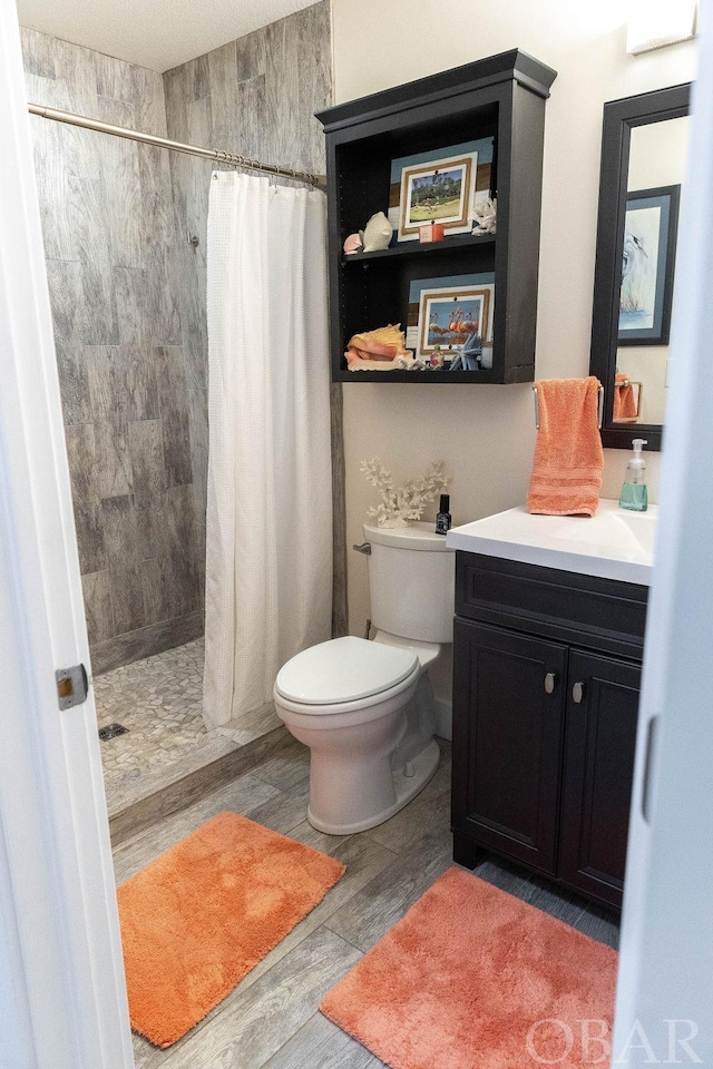 full bathroom with toilet, a shower stall, wood tiled floor, and vanity