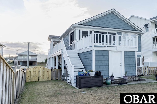 back of property with a yard, stairway, and a fenced backyard