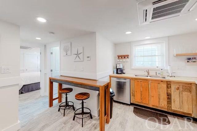 kitchen with light countertops, visible vents, stainless steel dishwasher, light wood-style floors, and a sink