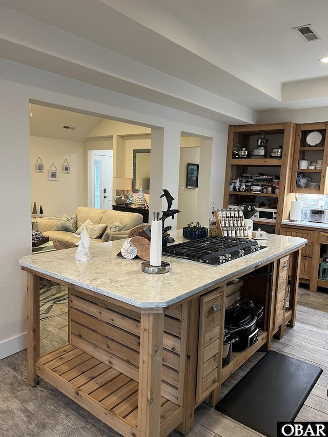 kitchen with visible vents, open floor plan, a center island, light wood-type flooring, and stainless steel gas stovetop