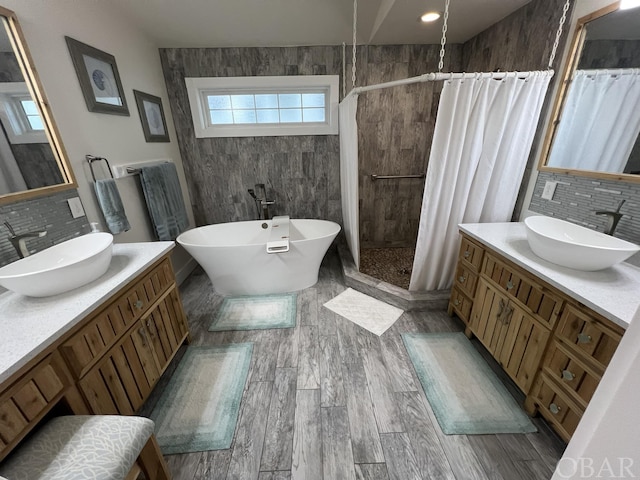 full bathroom with a freestanding tub, backsplash, a sink, and a shower stall