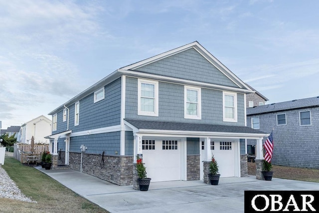 view of front facade featuring stone siding, driveway, an attached garage, and fence