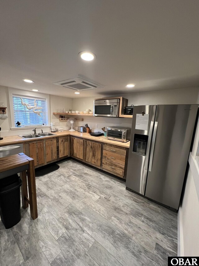 kitchen with appliances with stainless steel finishes, brown cabinets, light countertops, and a sink