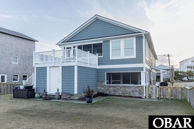 view of front of home featuring entry steps, stone siding, a front yard, and fence