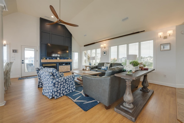 living area featuring a large fireplace, visible vents, plenty of natural light, and light wood finished floors