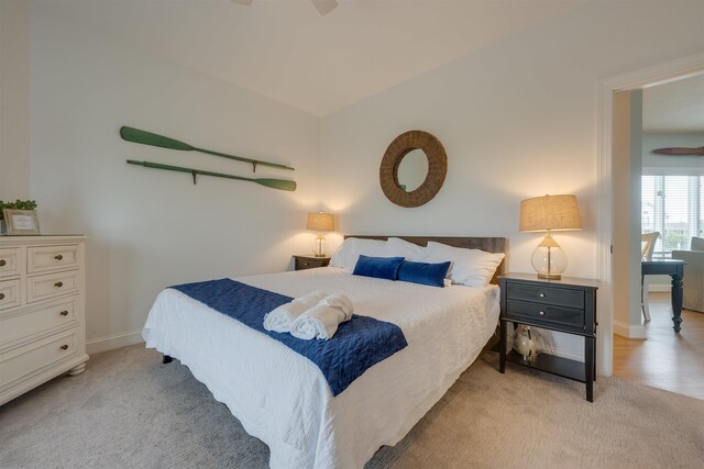 bedroom featuring baseboards, vaulted ceiling, and light colored carpet