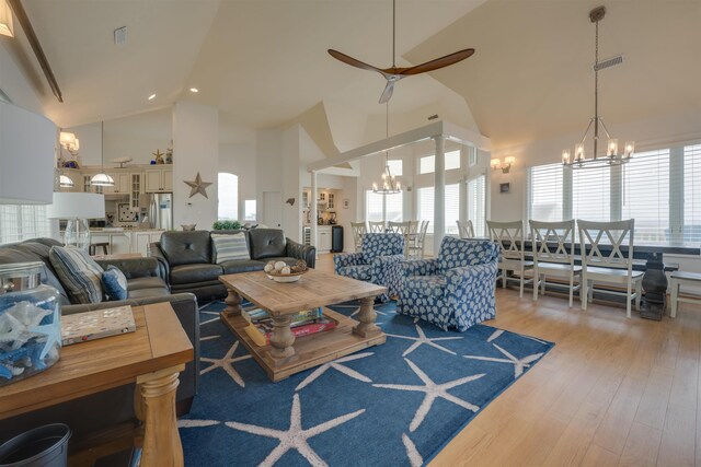 living area featuring light wood-style floors, visible vents, plenty of natural light, and high vaulted ceiling