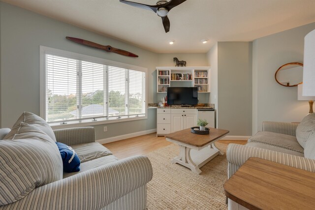 living area with light wood-style flooring, baseboards, and a ceiling fan