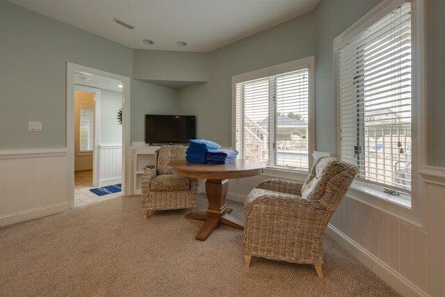 sitting room with light carpet, a wainscoted wall, and visible vents