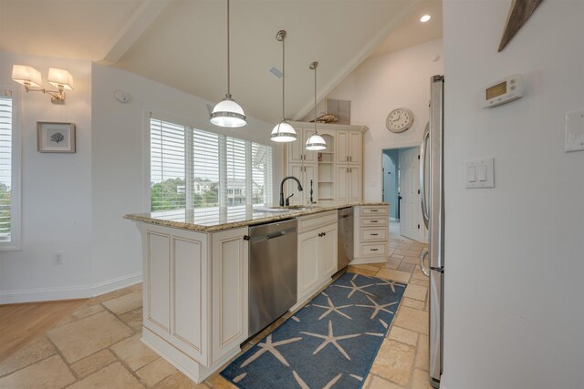 kitchen with stone tile floors, an island with sink, light stone counters, hanging light fixtures, and stainless steel appliances