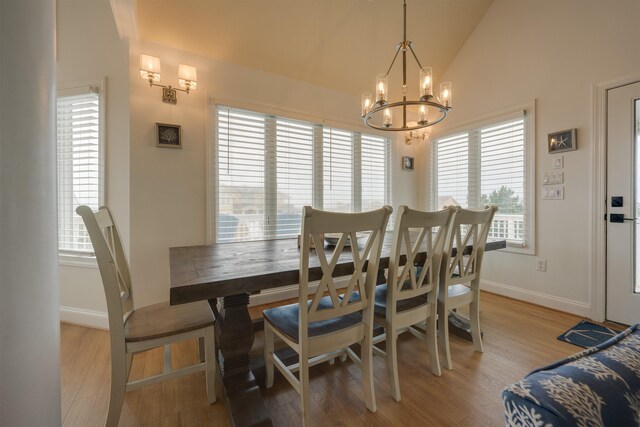 dining room featuring lofted ceiling, light wood finished floors, baseboards, and a chandelier