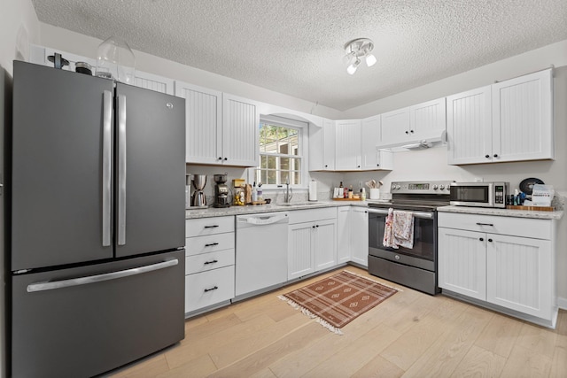 kitchen with appliances with stainless steel finishes, white cabinetry, light wood-style flooring, and under cabinet range hood