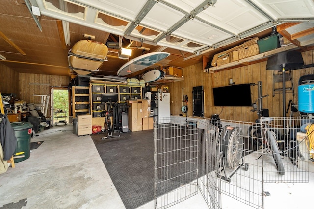 garage featuring wood walls, freestanding refrigerator, and a garage door opener