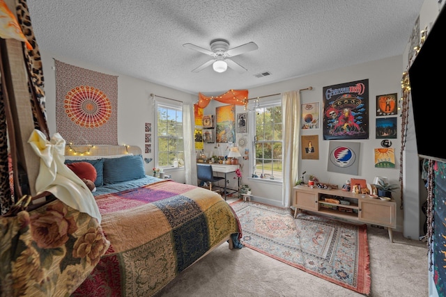 bedroom featuring ceiling fan, a textured ceiling, carpet, and visible vents