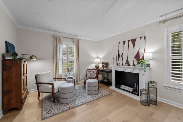 living area featuring a fireplace with raised hearth, a textured ceiling, wood finished floors, baseboards, and ornamental molding