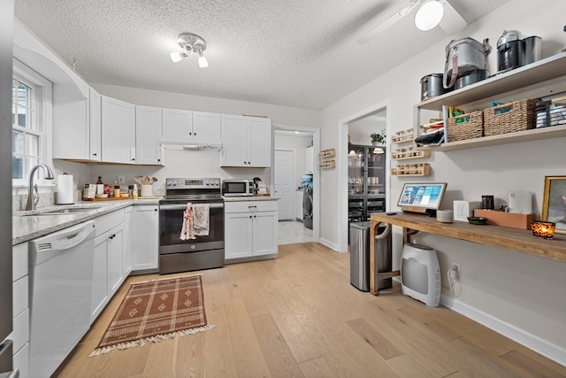 kitchen featuring light wood-type flooring, white cabinets, stainless steel appliances, and a sink