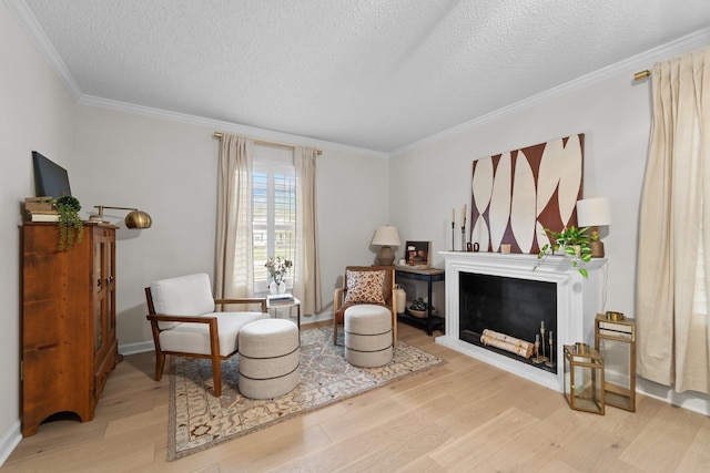 living area with a textured ceiling, light wood-type flooring, a fireplace, and crown molding