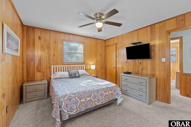 bedroom featuring ceiling fan, wood walls, carpet floors, and a textured ceiling