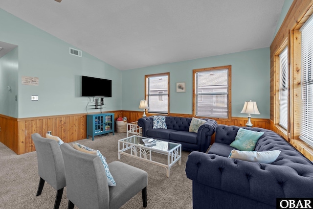 living area with visible vents, wainscoting, carpet, and vaulted ceiling