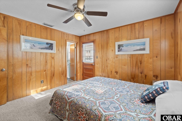 bedroom featuring wooden walls, carpet flooring, ceiling fan, and visible vents