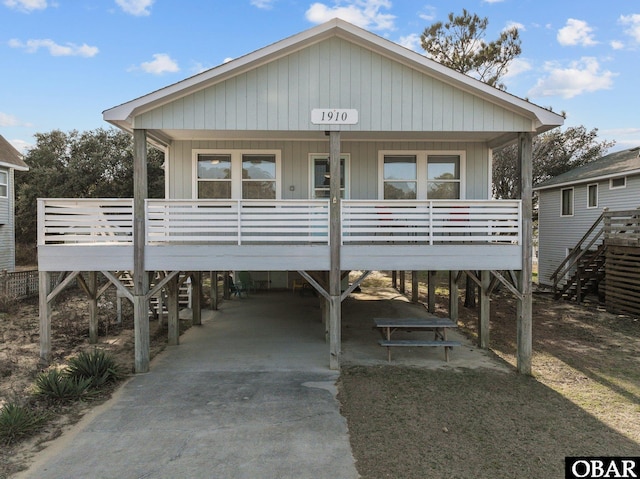 coastal inspired home with driveway, a carport, a porch, and stairs