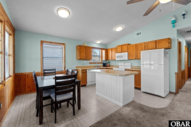 kitchen with white appliances, a wainscoted wall, visible vents, light countertops, and wood walls