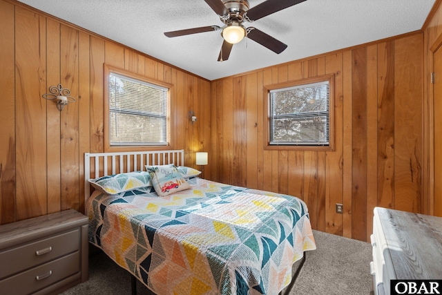 bedroom with ceiling fan, multiple windows, wood walls, and a textured ceiling