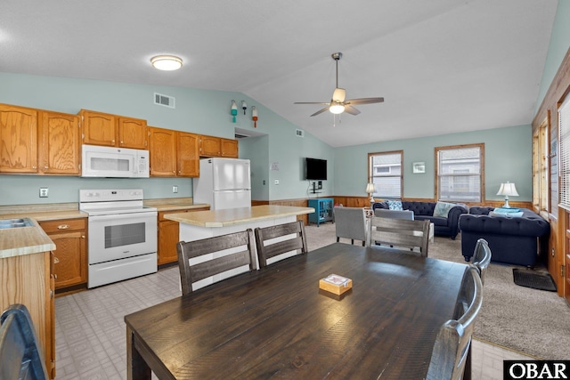 kitchen featuring open floor plan, light floors, light countertops, wainscoting, and white appliances