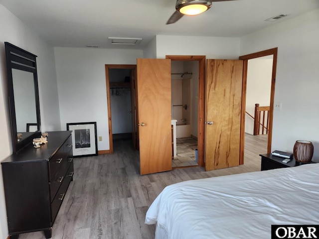 bedroom with a walk in closet, attic access, light wood-style floors, and visible vents
