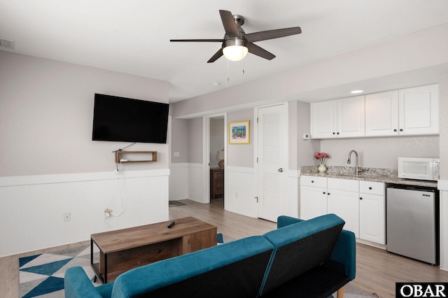 57241 Summerplace Dr Lot 28, Hatteras, NC 27943 - living area featuring a wainscoted wall, a ceiling fan, light wood-style flooring, and bar with sink