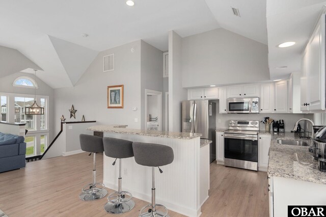 57241 Summerplace Dr Lot 28, Hatteras, NC 27943 - kitchen with stainless steel appliances, a sink, white cabinets, light stone countertops, and a kitchen bar