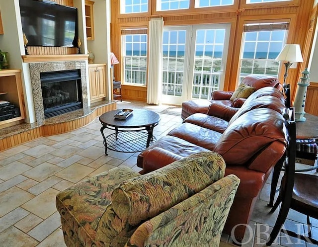 living area with a water view, stone tile floors, and a premium fireplace