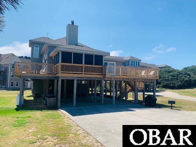 135 Ships Watch Dr Lot 32, Duck, NC 27949 - back of property with a carport, a chimney, a wooden deck, driveway, and a shingled roof