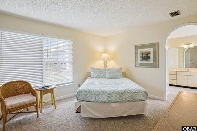 135 Ships Watch Dr Lot 32, Duck, NC 27949 - bedroom featuring light colored carpet, arched walkways, baseboards, ensuite bath, and a textured ceiling