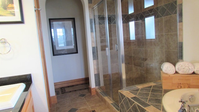 bathroom with a stall shower, plenty of natural light, baseboards, tile patterned floors, and vanity