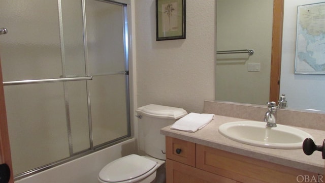 bathroom featuring toilet, shower / bath combination with glass door, and vanity