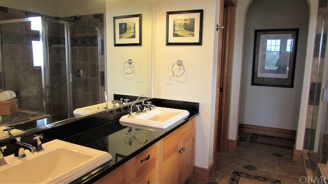 full bathroom with double vanity, a stall shower, and a sink