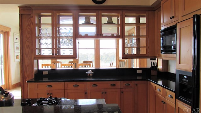 kitchen featuring dark stone counters, brown cabinetry, and built in appliances