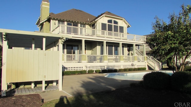 rear view of property featuring a chimney and a balcony