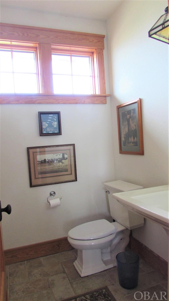 half bath featuring toilet, baseboards, and a wealth of natural light