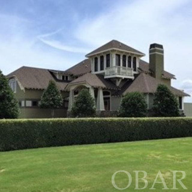 view of front of house featuring a balcony and a front lawn